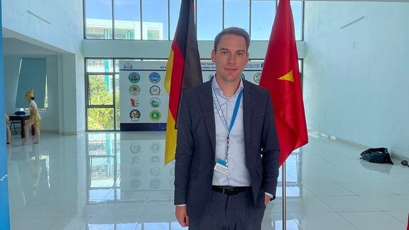 Kevin Holland-Moritz vor deutscher und vietnamesischer Flagge