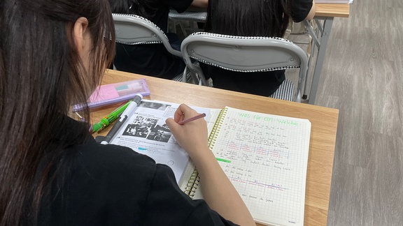 Eine Schülerin schreibt auf einem Block