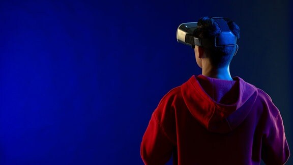 Ein Man mit Virtual-Reality-Brille in einem blau beleuchtete Raum