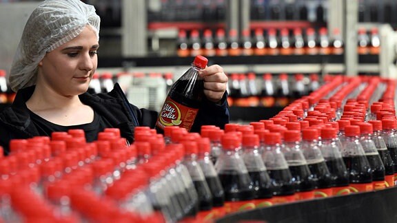 Kaja Müller, Mitarbeiterin der Thüringer Waldquell Mineralbrunnen GmbH, steht bei der Abfüllung von Vita-Cola an der Produktionsanlage.