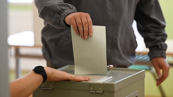 Ein Mann wirft seinen Stimmzettel in eine Wahlurne.