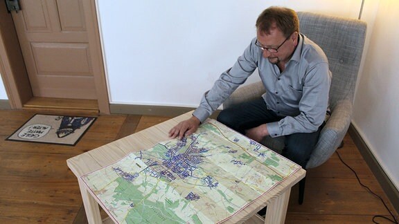 Wolfram Wiese sitzt vor einer Karte von Weimar