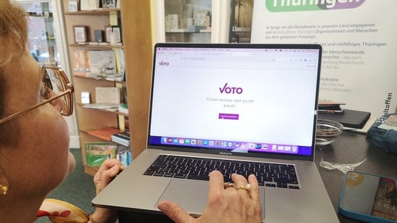 Eine ältere Frau mit Brille ruft eine Webseite auf ihrem Laptop auf. Es ist die Seite Voto.vote.