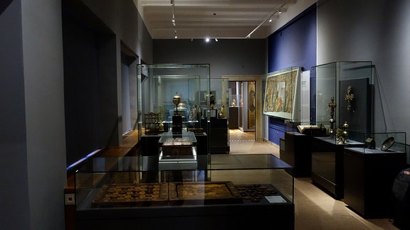 Der zweite große Raum ist dem Kunsthandwerk gewidmet und soll so aussehen wie eine Schatzkammer. Er wirkt dunkel, damit die Ausstellungsstücke besser zur Geltung kommen können.