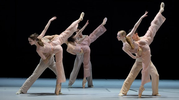 Ballettszene, drei Tanzpaare, die Tänzerinnen strecken ein Bein weit hinter sich nach oben über Kopfhöhe