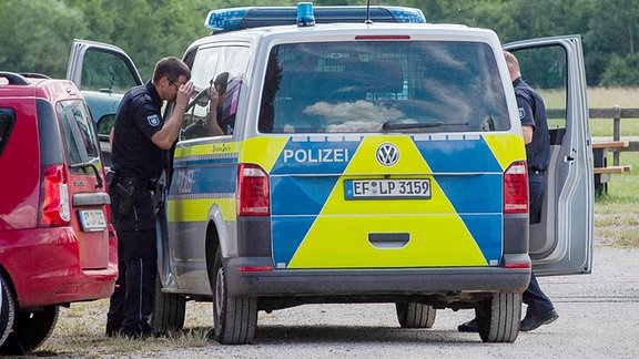 Polizisten stehen neben ihrem Auto auf dem Gelände einer Fallschirmschule bei Eisenach