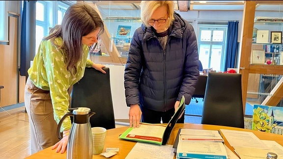 Eisenacher Oberbürgermeisterin Katja Wolf und eine Mitarbeiterin stehen an einem Tisch und blättern durch Papiere.