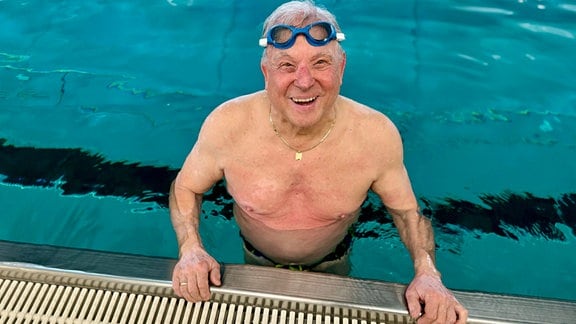 Ein Mann steht in einem Schwimmbecken und lächelt.