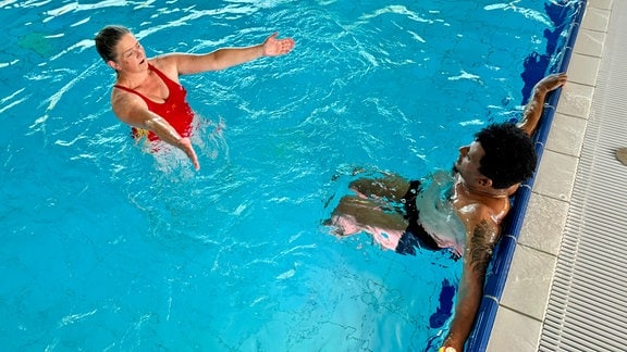 Eine Frau hilft einem Mann mit Schwimmübungen