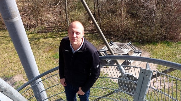 Ein Mann steht im Freien auf einer Wendeltreppe aus Metall