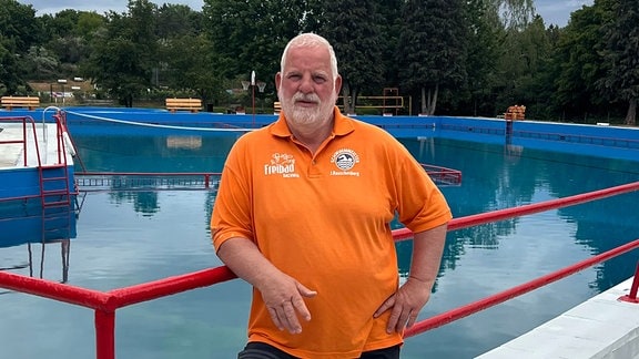 Bademeister Jörg Rauschenberg im Freibad mit orangem Shirt.