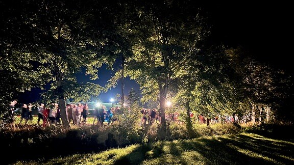 Menschen laufen auf einer Wiese durch die Nacht.