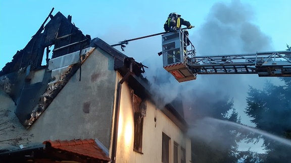 Die Feuerwehr löscht an einem abgebrannten Haus.