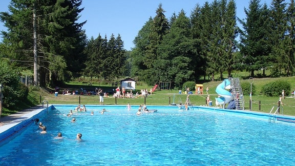 Schwimmbecken mit Rutsche und Spielplatz.