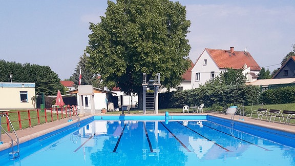 Schwimmbecken mit Sprungturm sowie Liegeflächen.