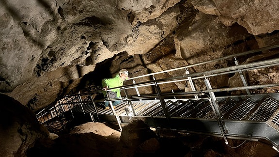 Eine Frau steigt eine Treppe im Innern der Höhle herauf.