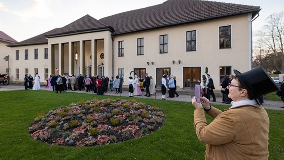 Menschen in historischen Kostümen stehen vor dem Portal eines Gebäudes, das als Comödienhaus Bad Liebenstein bekannt ist
