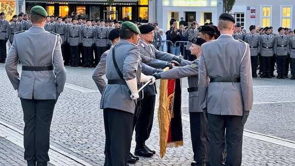 Eine Abordnung der Bundeswehr-Rekruten auf dem Eisenacher Marktplatz legt das feierliche Gelöbnis mit der Hand an der Truppenfahne ab.