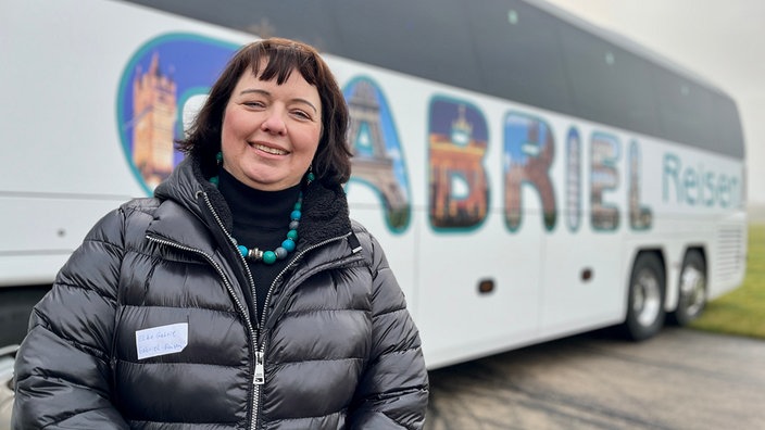 Eine Frau steht vor einem Bus.