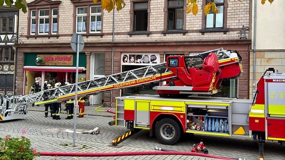 Feuerwehrauto mit Drehleiter und Feuerwehrleute vor einem Haus in Eisenach