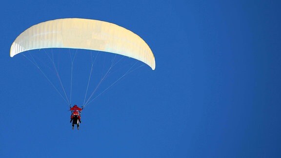 Ein Tandemflieger ist mit zwei Personen in der Luft