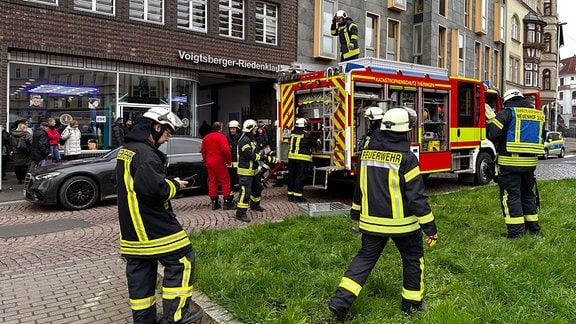 Feuerwehrfahrzeuge und Feuerwehrleute vor Gebäuden