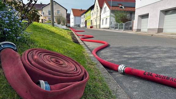 Ein langer Feuerwehrschlauch liegt auf einer Straße.