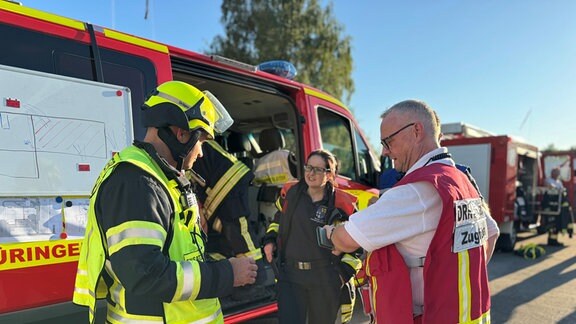 Ehemalige Großdiscothek MAD in Eisenach brennt: Einsatzleiter Markus Weigelt (links) bespricht die Einsatzlage mit Christine Richter vom Brand- und Katastrophenschutz im Landratsamt des Wartburgkreises, sowie mit Kreisbereitschaftsleiter Olaf Braun (rechts) vom Sanitäts- und Betreuungszug des DRK-Kreisverbandes Eisenach.