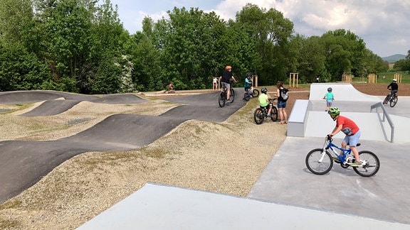 Kinder mit Fahrrädern auf Skater- und Mountainbike-Anlage