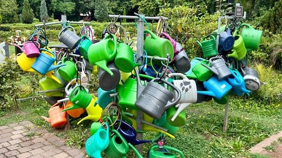 Viele bunte Gießkannen hängen am Eisenacher Friedhof.