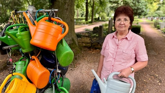 Friedhofsbesucherin Ilona Schmidt hält ihre eigene Gießkanne in der Hand, die sie immer auf den Friedhof mitbringt.