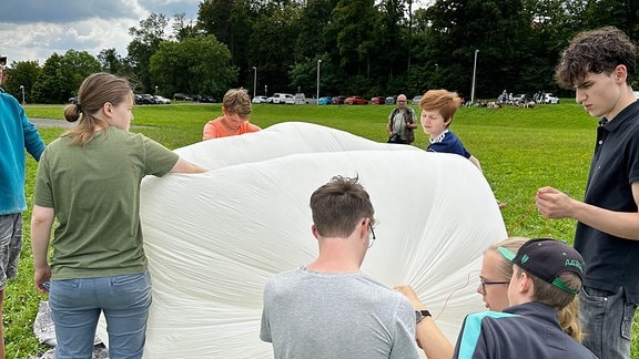 Der Wetterballon wurde mit Helium gefüllt, um bis zu 36.000 Meter in die Stratosphäre zu steigen. Schülerinnen und Schüler hielten ihn am Boden.