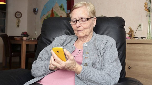 Seniorin schaut auf Smartphone