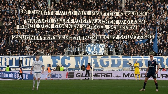 Magdeburger Fans zeigen einen Spruchbanner Im Einsatz wild mit Pfeffer streuen - danach alles überwachen wollen - doch den eigenen Spiegel scheuen - Zeugnisverweigerungsrecht schützen!