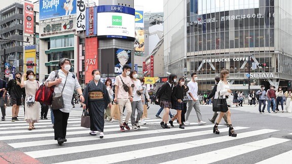 Menschen laufen über eine Straße in Tokio