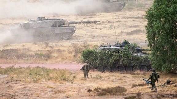 Zwei Kampfpanzer der Bundeswehr vom Typ Leopard 2 fahren auf einem Truppenübungsplatz