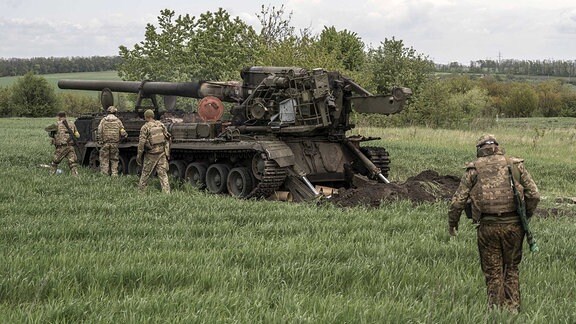 Ukrainische Soldaten vor einem zerstörten schweren ukrainischen 2S7-Geschütz
