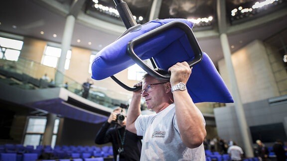 Ein Mann trägt beim Umbau des Plenarsaales des Deutschen Bundestages einen Stuhl