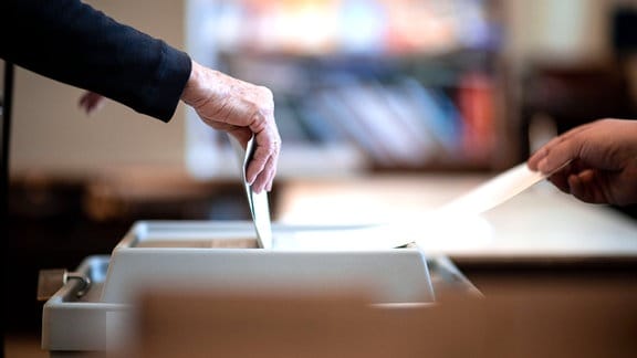 Eine Frau wirft ihren Stimmzettel in eine Wahlurne