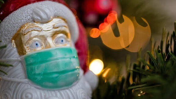 Weihnachtsschmuck in Form eines Weihnachtsmannes, der eine Maske trägt
