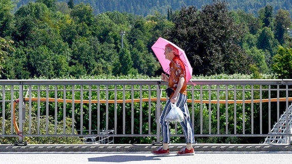 Person mit Regenschirm gegen Hitze, Schweiz