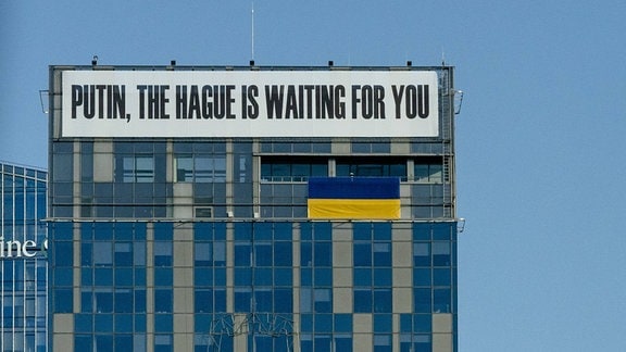 Banner mit Aufschrift 'Putin, The Hague is waiting for you.' an einem Gebäude in Litauen