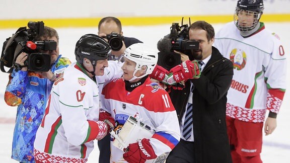 Alexander Lukaschenko und Wladimir Putin umarmen sich in Eishockey-Montur.