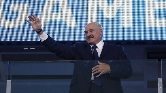 Alexander Lukaschenko hebt grüßend den Arm. Auf einer Stadionanzeige hinter ihm steht "Game".