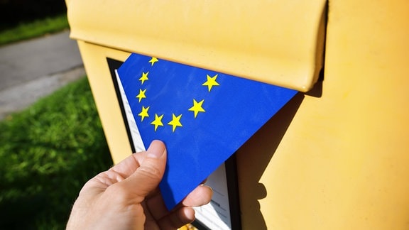 Europa-Fahne wird in einen Briefkasten geworfen.