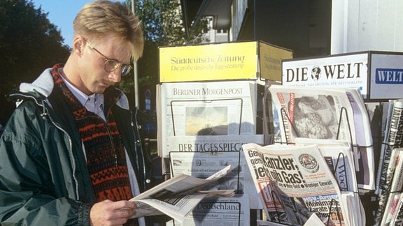 Ein Mann liest an einem Kiosk eine Zeitung