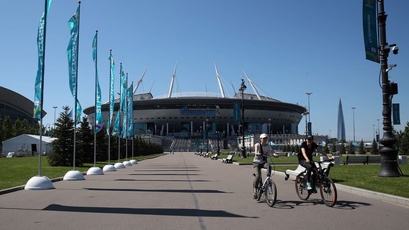  Zwei Radler fahren vor der Gazprom Arena in Sankt Petersburg