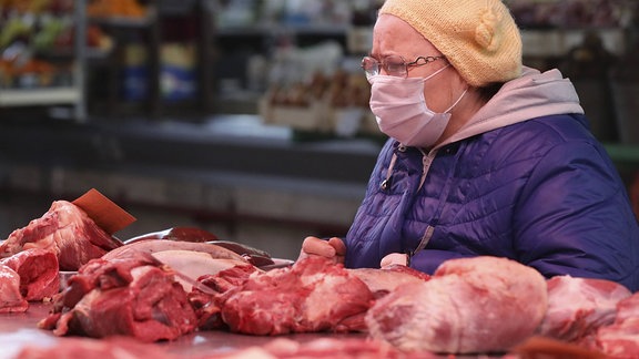 Eine ältere Frau, die Fleisch auf dem Oktyabrsky-Lebensmittelmarkt einkauft. 