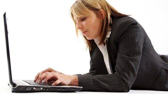 Junge Geschäftsfrau arbeitet 2008, auf dem Boden liegend, am Laptop.