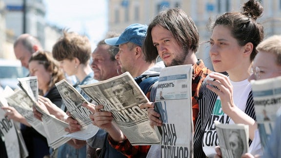 Menschen halten Zeitungen in den Händen.